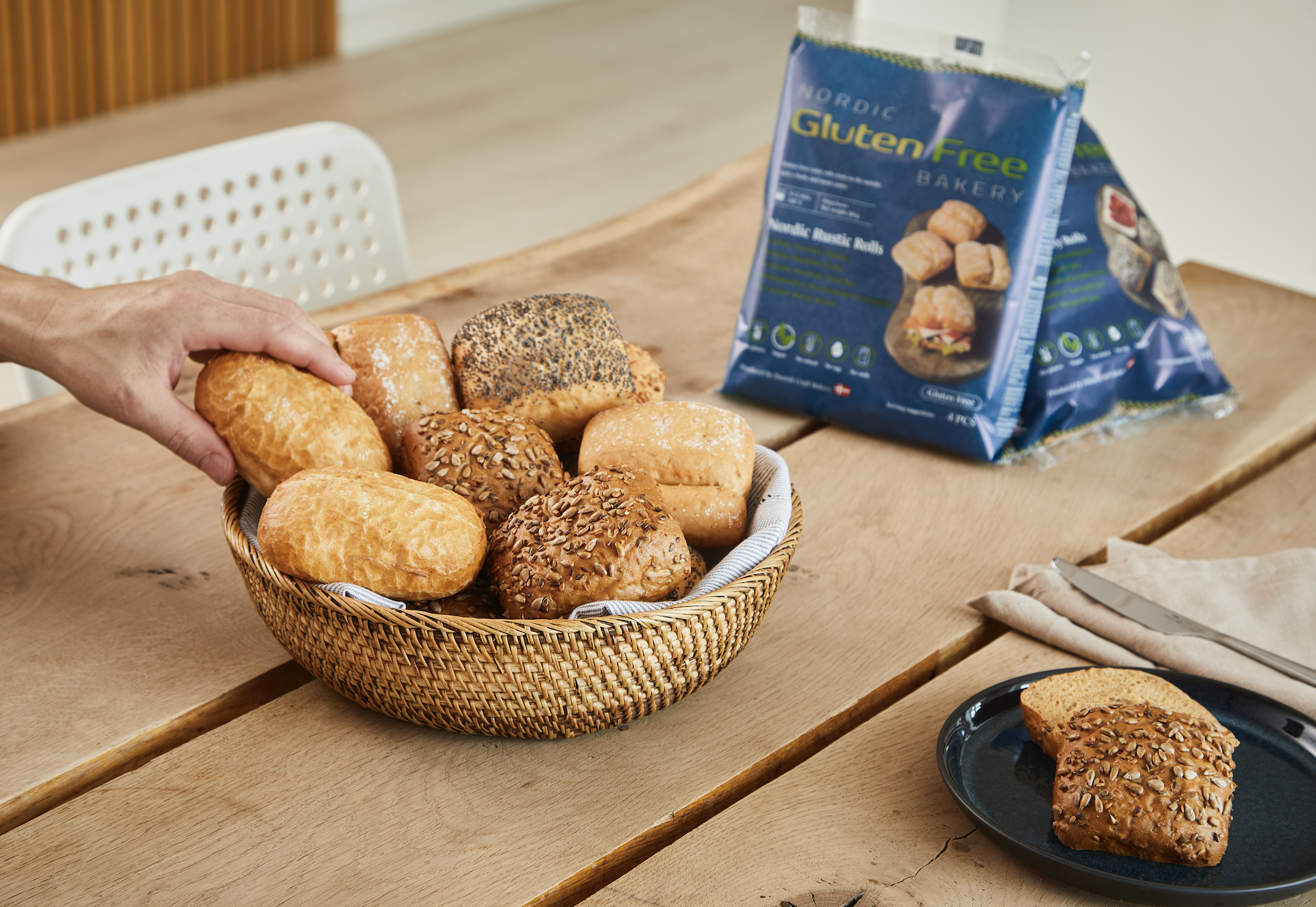 Assorted gluten free Nordic rustic rolls in a basket next to Nordic Gluten Free Bakery retail packaging
